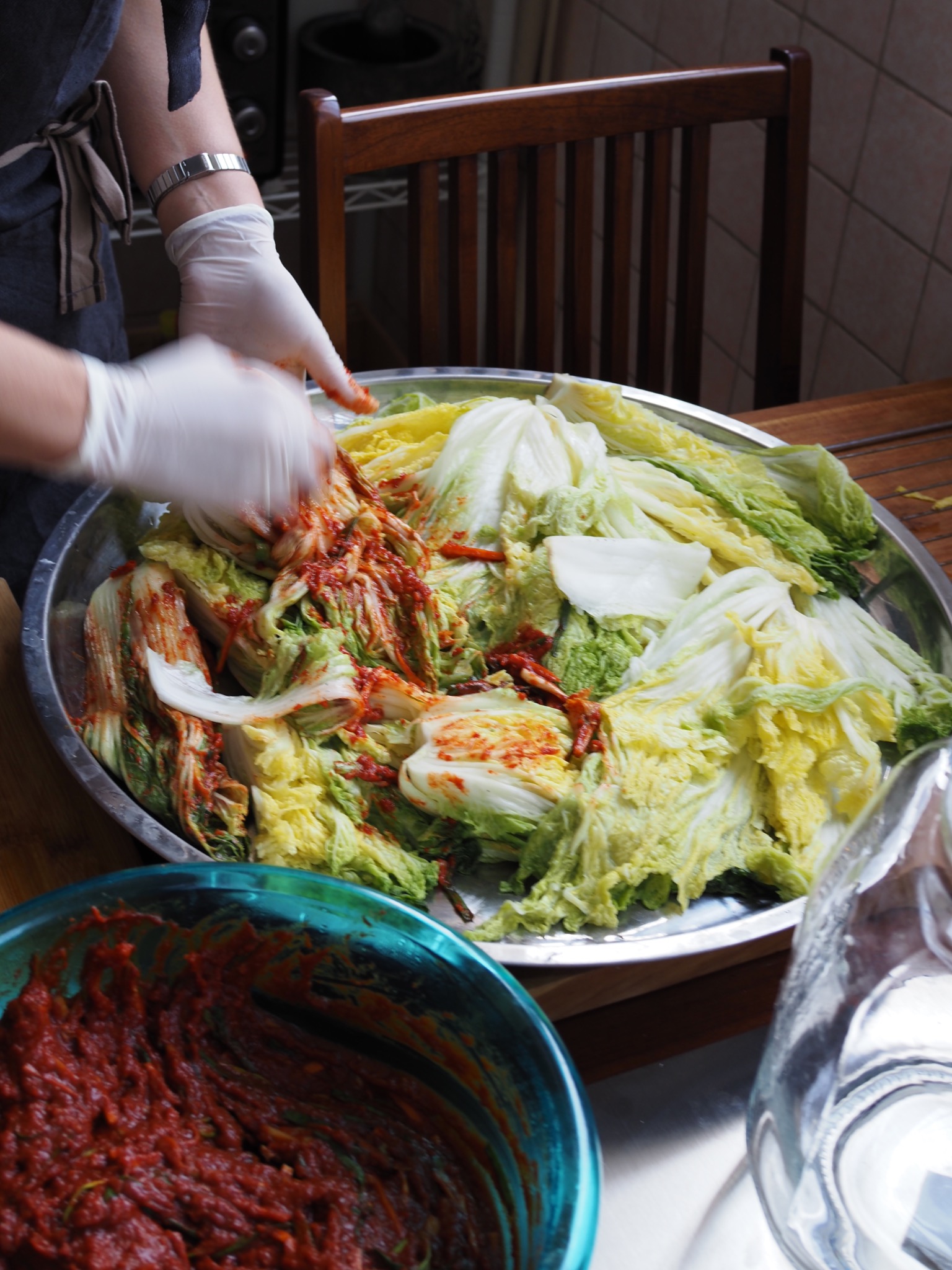 Kimchi paste being spread between napa cabbage leaves